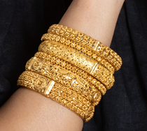 Six gold bangles on a wrist